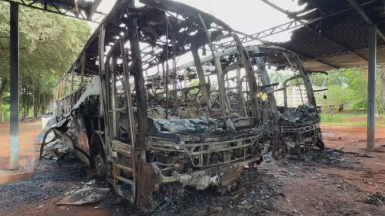 Polícia investiga incêndio criminoso em ônibus após câmera flagrar homem pulando portão com galão
