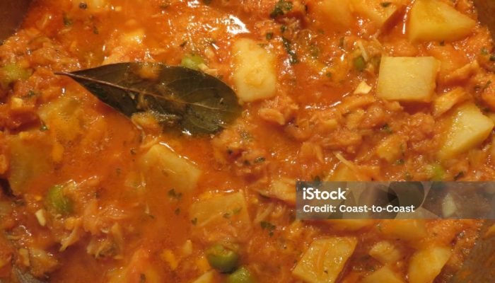 Photo of Easter dinner food being cooked in a pot.  This is Bacalao or salted codfish with olives, potatoes, parsley, tomato sauce, bay leaves and onions.  This is typical Easter dinner food in Mexico, Spain, Portugal and other countries where spanish is spoken.  It is also prepared in the United States by spanish speaking people.  This pot of Bacalao is enough for 2-3 dinners and is served over bread.  A typical side dish served with the Bacalao is rapini.